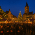 Magische Europese kerstmarkt met sfeervolle lichtjes, houten kraampjes, glühwein en een grote verlichte kerstboom in een historische stad.